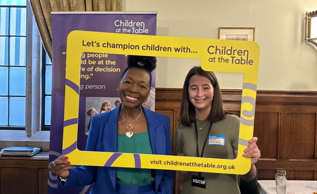 Baroness Floella Benjamin stands with Children at the Table frame with another young person