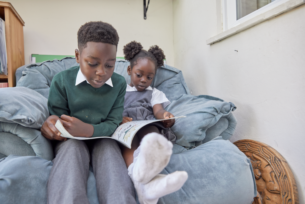 A brother and sister reading a workbook together.